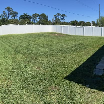 Clean mowed backyard in Fort Pierce FL with white vinyl fence